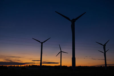 Power generators of windmills at shadow sunset - wind turbine on field at sunset