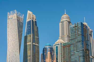 Low angle view of modern buildings against blue sky