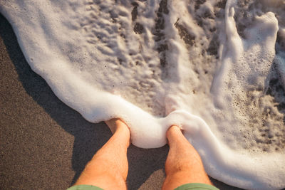 Low section of man standing at shore