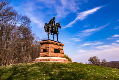 Low angle view of black human and animal statue against blue sky at valley forge national park