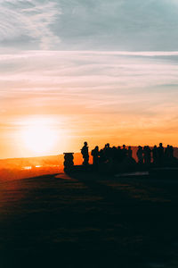 Silhouette people on field against sky during sunset