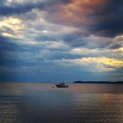 Silhouette of boat in sea against cloudy sky