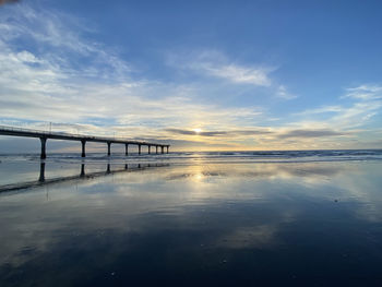 Bridge over sea against sky during sunset