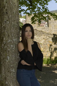 Portrait of woman standing on tree trunk