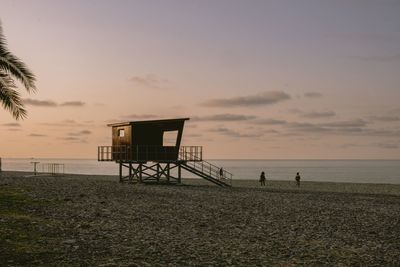 Lifeguard hut on beach against sky during sunset