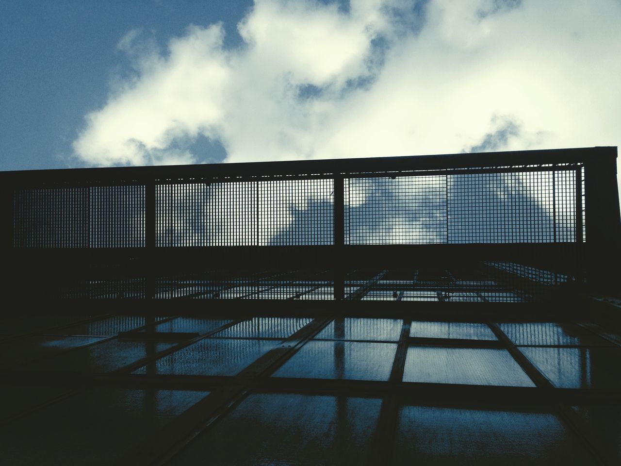 architecture, built structure, sky, building exterior, low angle view, window, cloud - sky, glass - material, building, cloud, railing, day, no people, city, outdoors, reflection, pattern, modern, cloudy, sunlight