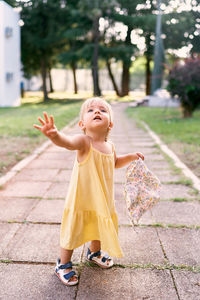 Full length of woman with arms raised on footpath