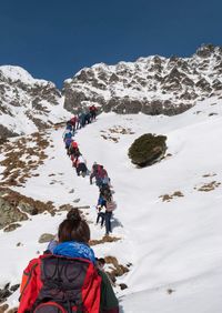 Rear view of people on snowcapped mountain