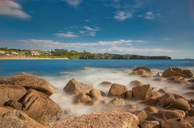 Scenic view of rocks on beach against sky