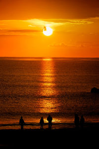 Silhouette people at beach during sunset