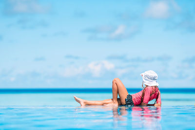 Woman swimming in pool against sea