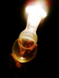 Close-up of illuminated light bulb against black background