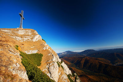 Low angle view of cross on bucegi mountains against clear blue sky