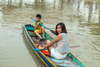 Portrait of mother with son sitting in boat on lake