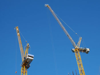 Low angle view of crane against clear blue sky