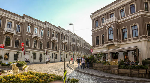 People on street amidst buildings against sky