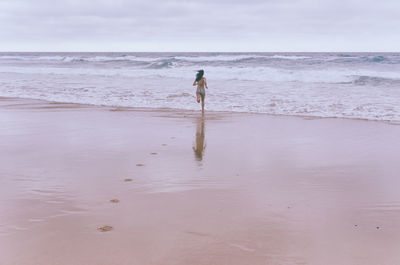 Rear view of woman running on shore at beach