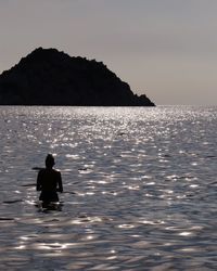 Rear view of silhouette man in sea against sky