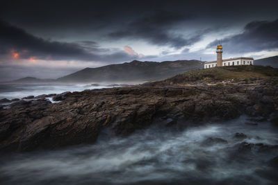 Lighthouse by sea against sky