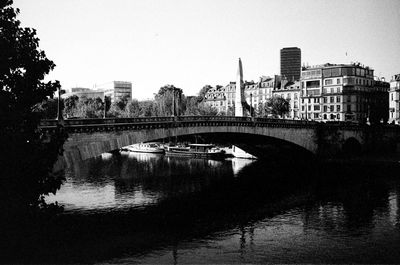 Bridge over river in city against clear sky