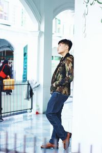 Side view of young woman standing against building