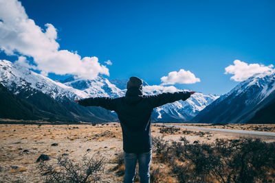 Man standing on field against snowcapped mountains