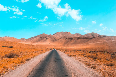 Road amidst desert against sky