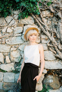 Portrait of young woman standing against rock