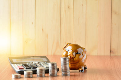 Coins stacked by piggy bank and calculator on table