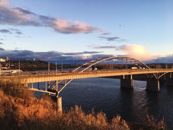 Bridge over river against cloudy sky