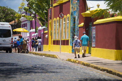 Rear view of people walking on road in city