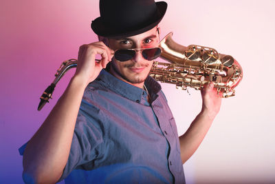 Portrait of man holding saxophone wearing hat