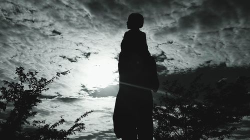 Silhouette man standing by tree against sky