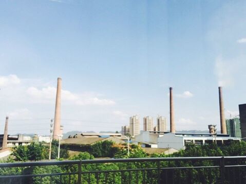 architecture, built structure, building exterior, factory, industry, smoke stack, railing, development, sky, tower, city, tall - high, day, outdoors, industrial building, air pollution, blue, cloud - sky, skyscraper, tall, urban skyline, office building, industrial, modern