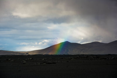 Scenic view of rainbow over land against sky