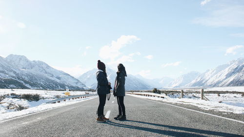 Rear view of woman standing on road against sky