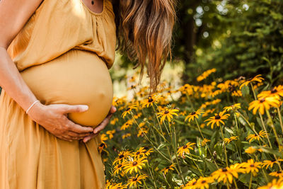 Midsection of pregnant woman holding stomach while standing outdoors