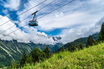 Low angle view of ski lift against cloudy sky