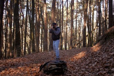 Man photographing with camera against trees in forest