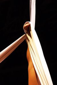 Low section of woman performing aerial silk against black background