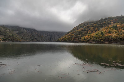 Scenic view of lake by mountains against sky