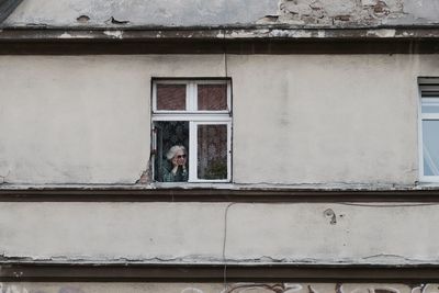 Man standing on window of building