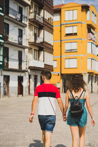 Rear view of couple holding hand walking on street