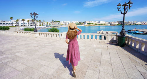 Rear view of woman with umbrella in city against sky