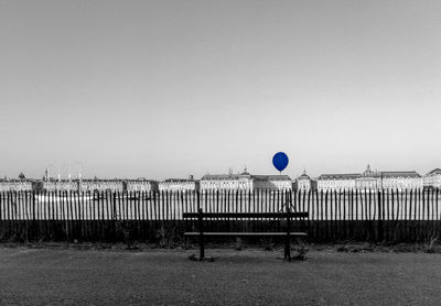 Balloons on field by sea against clear sky