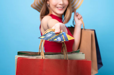 Close-up of woman holding red and blue against gray background