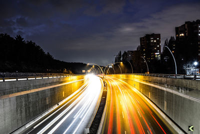 Light trails on road in city against sky at night