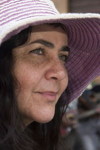 Close-up of a woman's face wearing pink hat and looking to the side. 