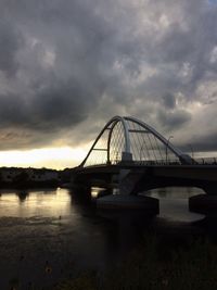 Bridge over river against cloudy sky
