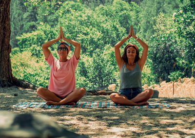 Two women doing yoga exercises in the nature. adults sitting in lotus position.